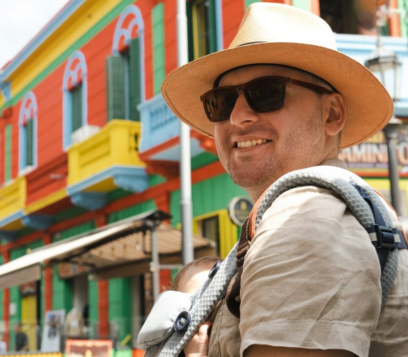 Caucasian happy man, father carrying little newborn baby in carrier,family traveling