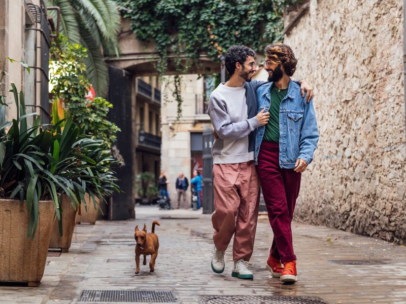 gay male couple walking with their dog. LGBTQ+ travel with Velvet